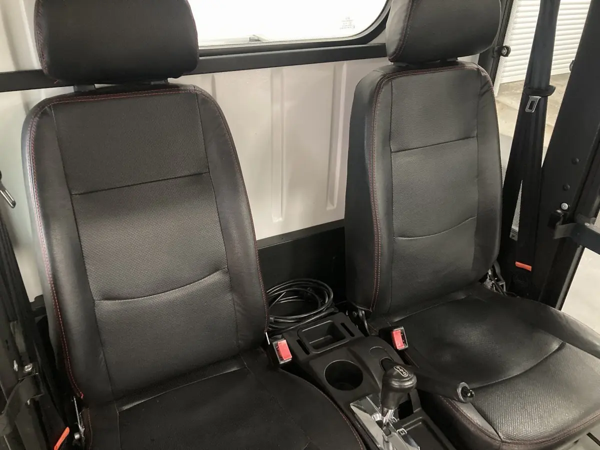 Vue intérieure rapprochée des sièges noirs avec coutures rouges du Liberty L7E H2 160 blanc, version Kit Ridelles.