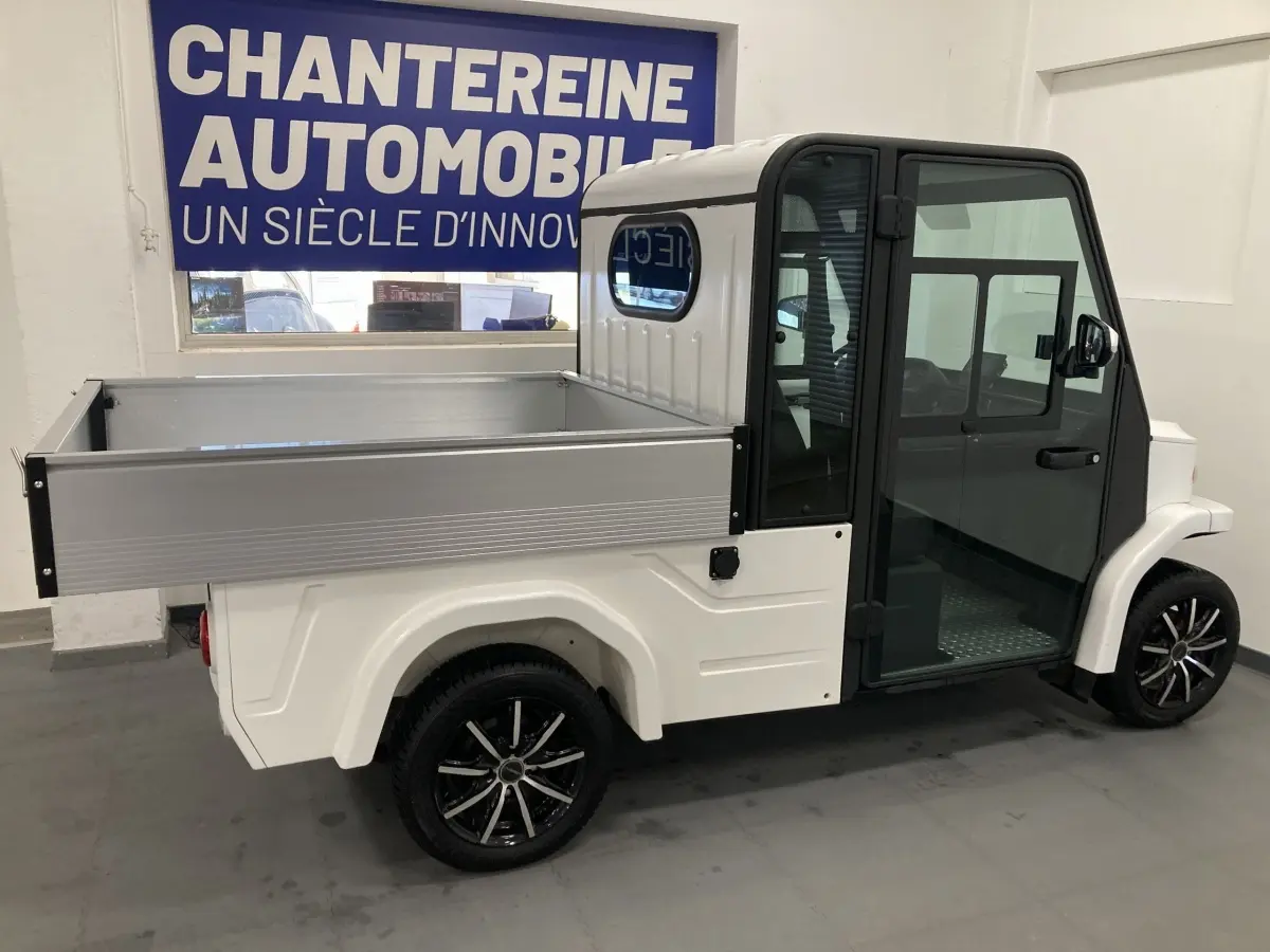 Vue de profil droit d’un utilitaire électrique blanc Liberty L7E H2 160 avec kit ridelles et jantes alliage 13 pouces.