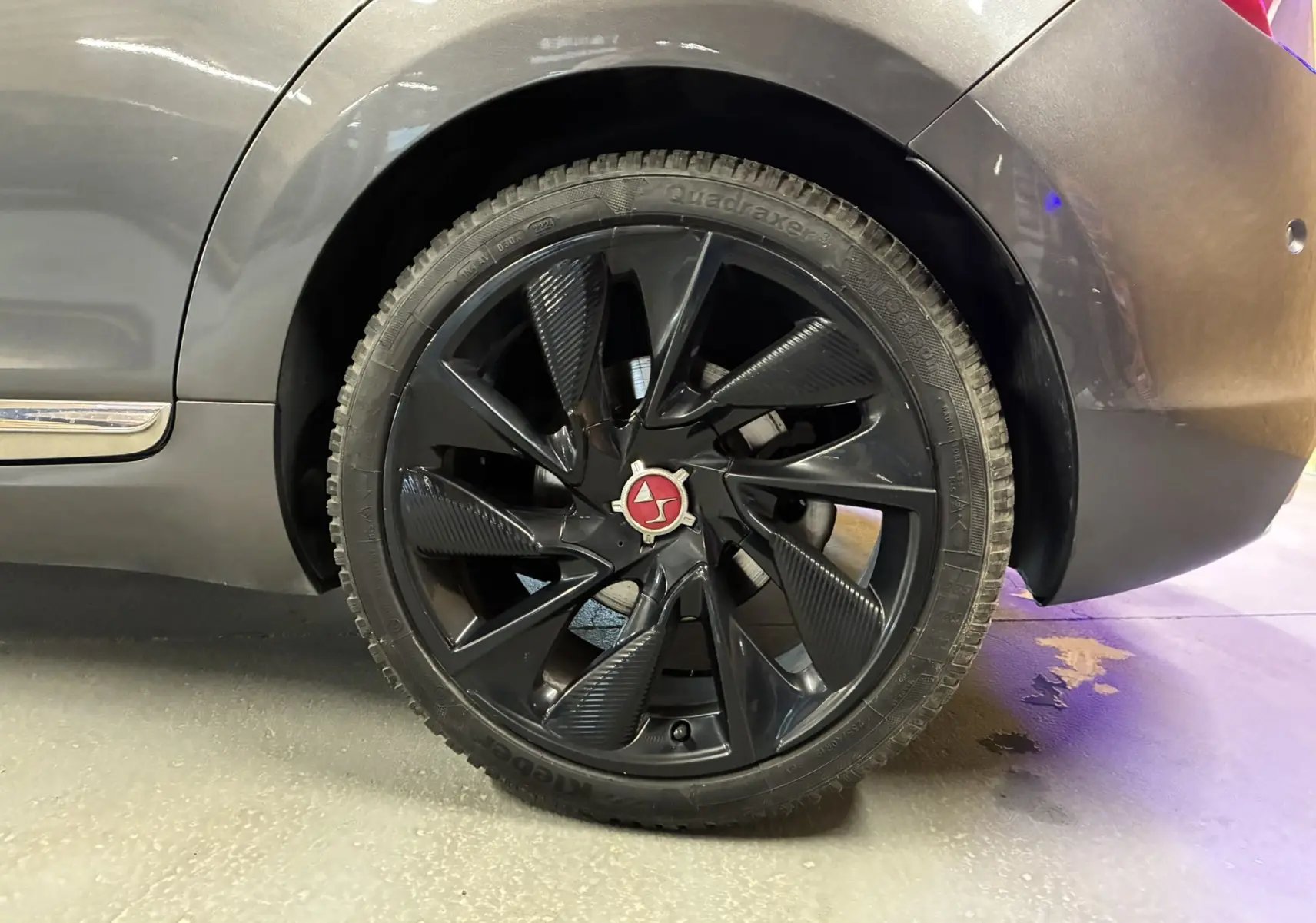 Gros plan sur la roue arrière droite noire à jante design du DS5 gris 2018, mettant en valeur le logo central rouge.