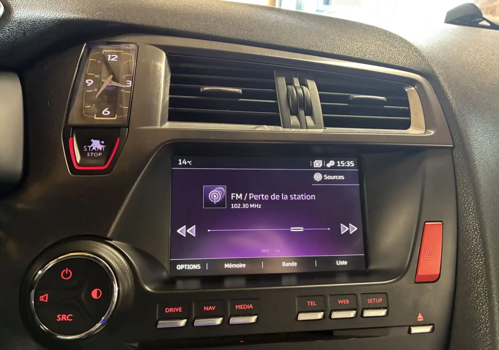 Vue rapprochée du tableau de bord gris du DS5 2018 avec écran tactile, horloge analogique et commandes rouges éclairées.