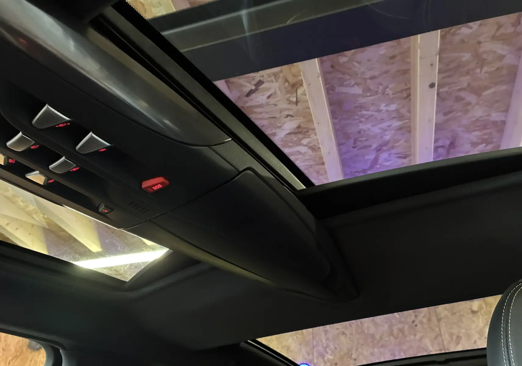 Vue intérieure du toit ouvrant panoramique et des commandes au plafond d'une DS5 gris 2018, ambiance sombre.