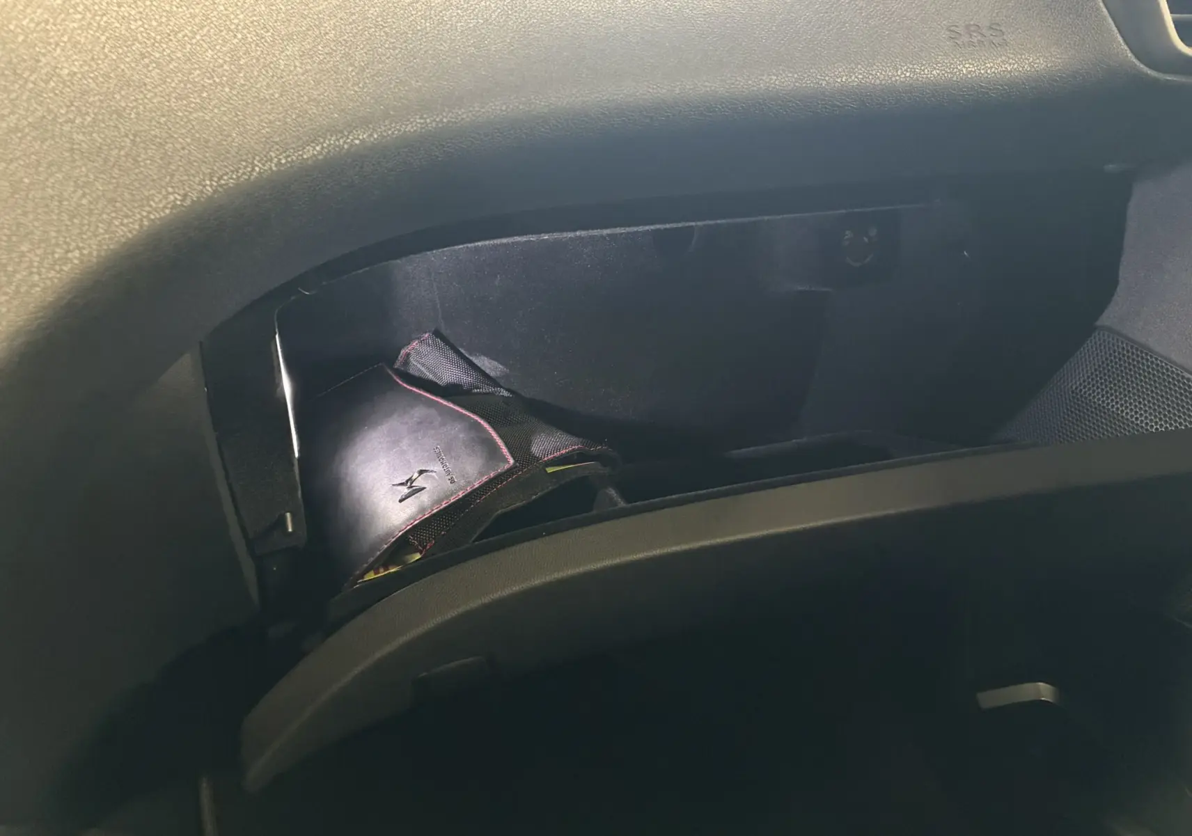 Vue intérieure du coffre à gants ouvert d'une DS5 gris, montrant un carnet de bord noir avec logo DS brodé.