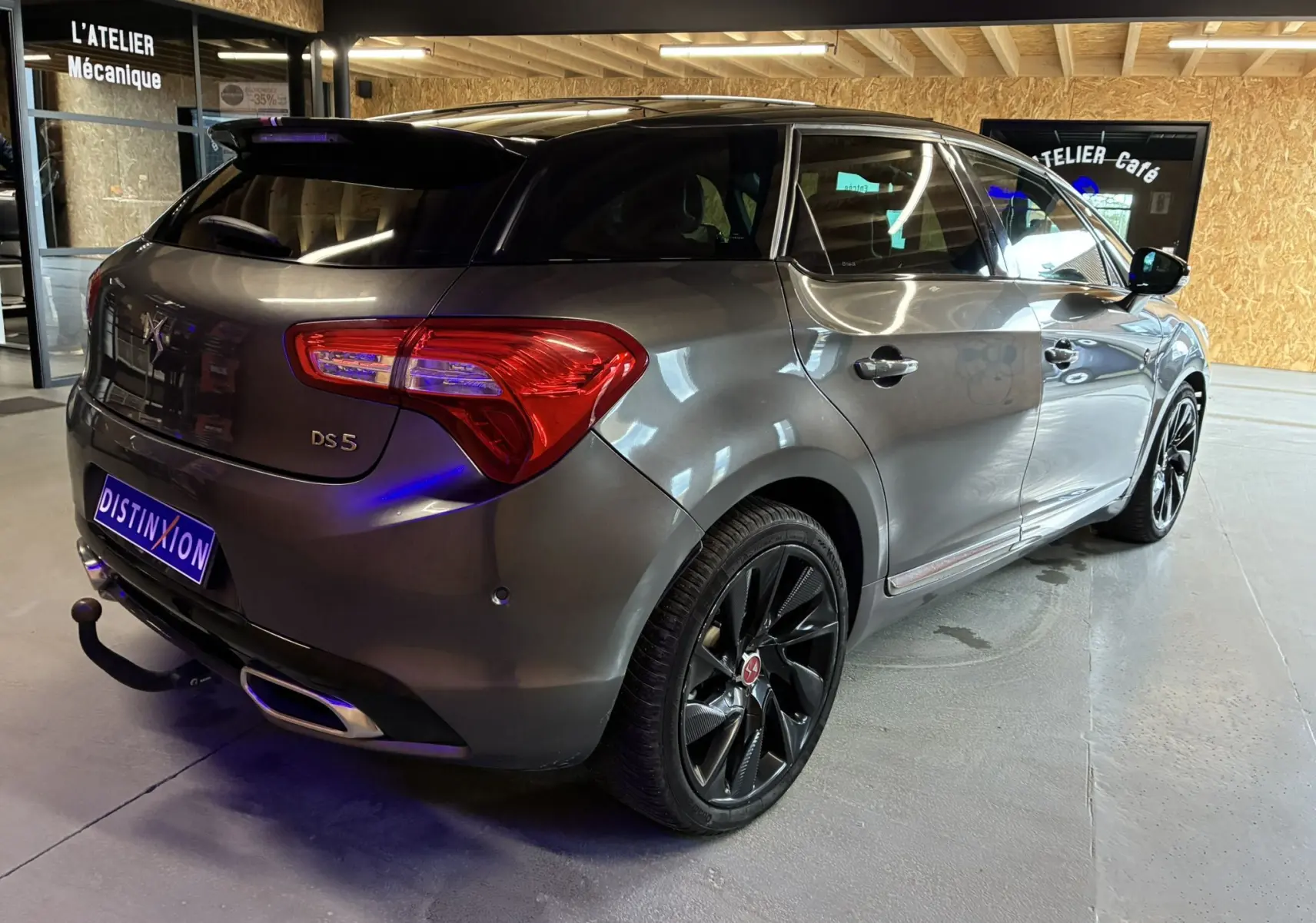 Vue 3/4 arrière droite d'une DS5 gris métallisé avec jantes noires et attelage dans un garage.