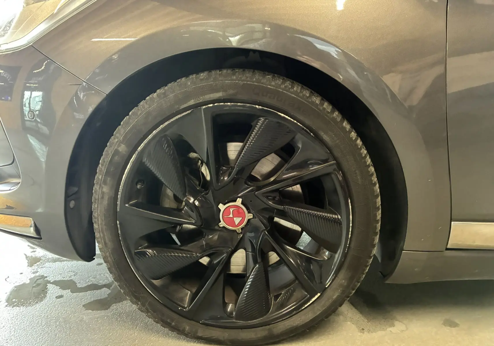 Gros plan sur la roue avant gauche noire à jante noire brillante du DS5 gris 2018, mettant en valeur le logo central rouge.