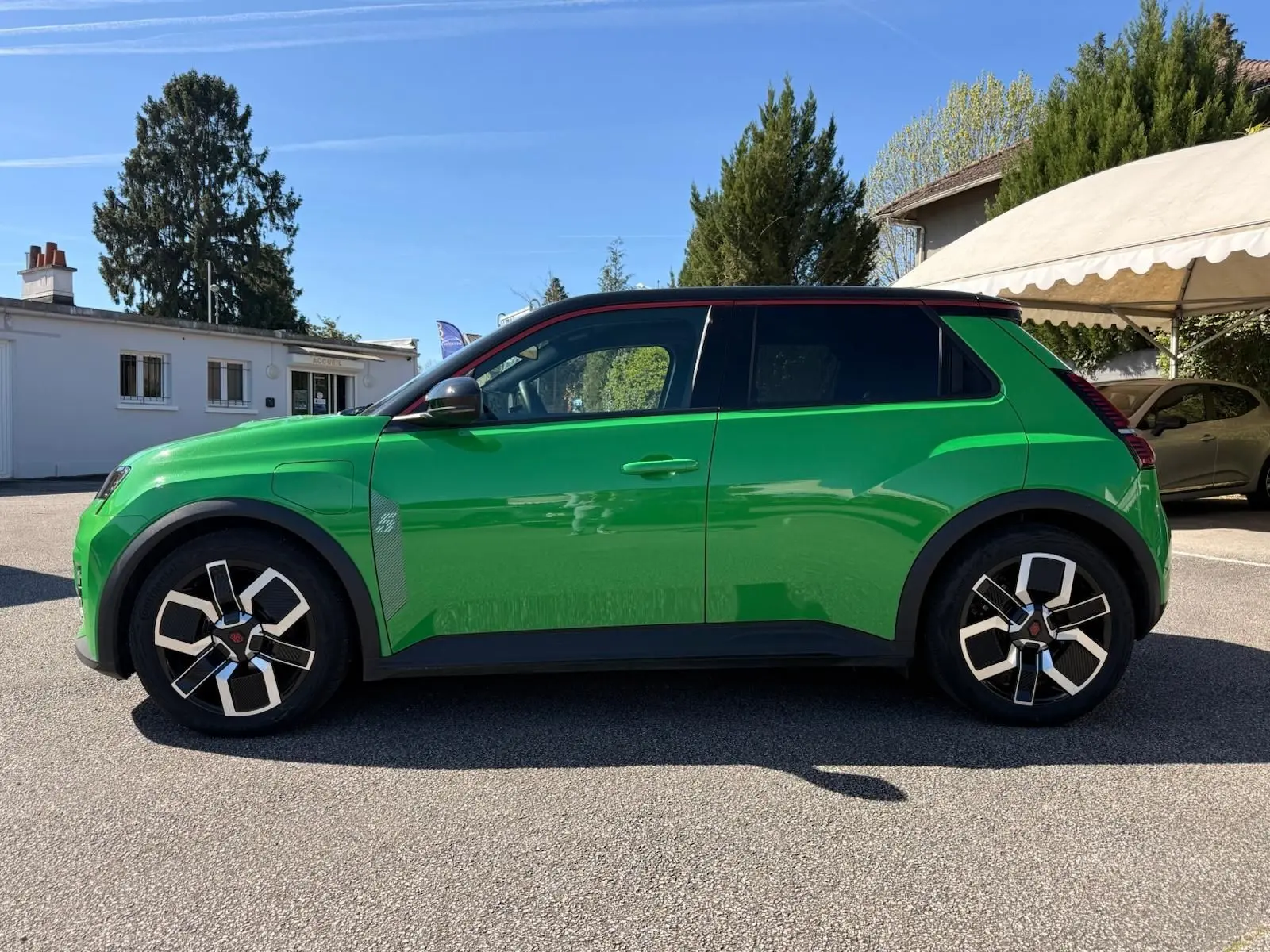 Profil côté gauche de la Renault R5 E-TECH électrique 2024 en vert Pop avec toit noir étoile et jonc de toit rouge alu.