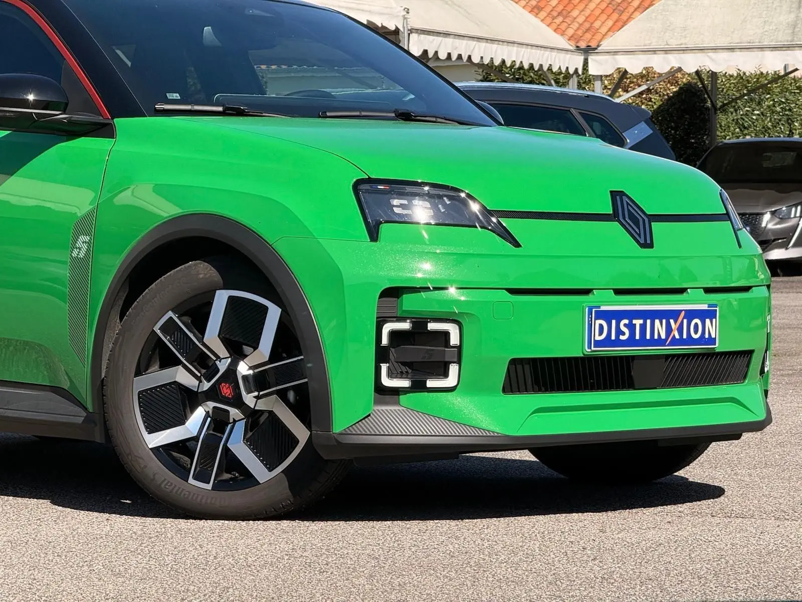 Vue 3/4 avant gauche d'une Renault R5 E-TECH électrique vert Pop avec jantes bi-ton et toit noir étoile.