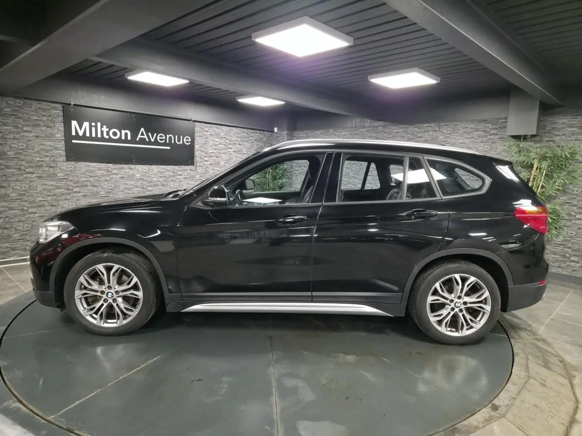 BMW X1 xDrive 25d noir vue de profil côté gauche, avec jantes alliage 18'' style 566 à rayons en Y.