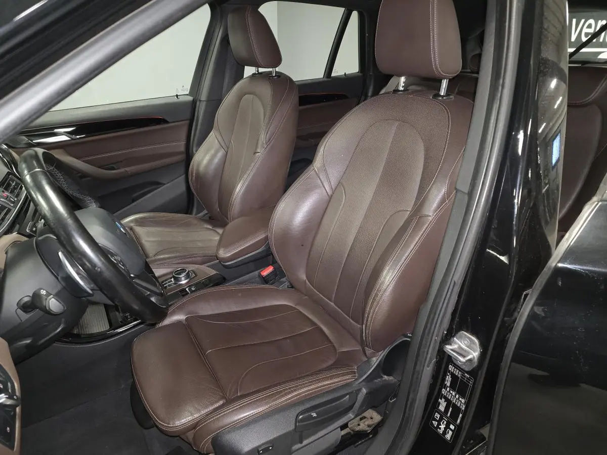 Vue intérieure côté conducteur du BMW X1 xDrive 25d 2016 avec sellerie cuir Dakota marron et tableau de bord noir.