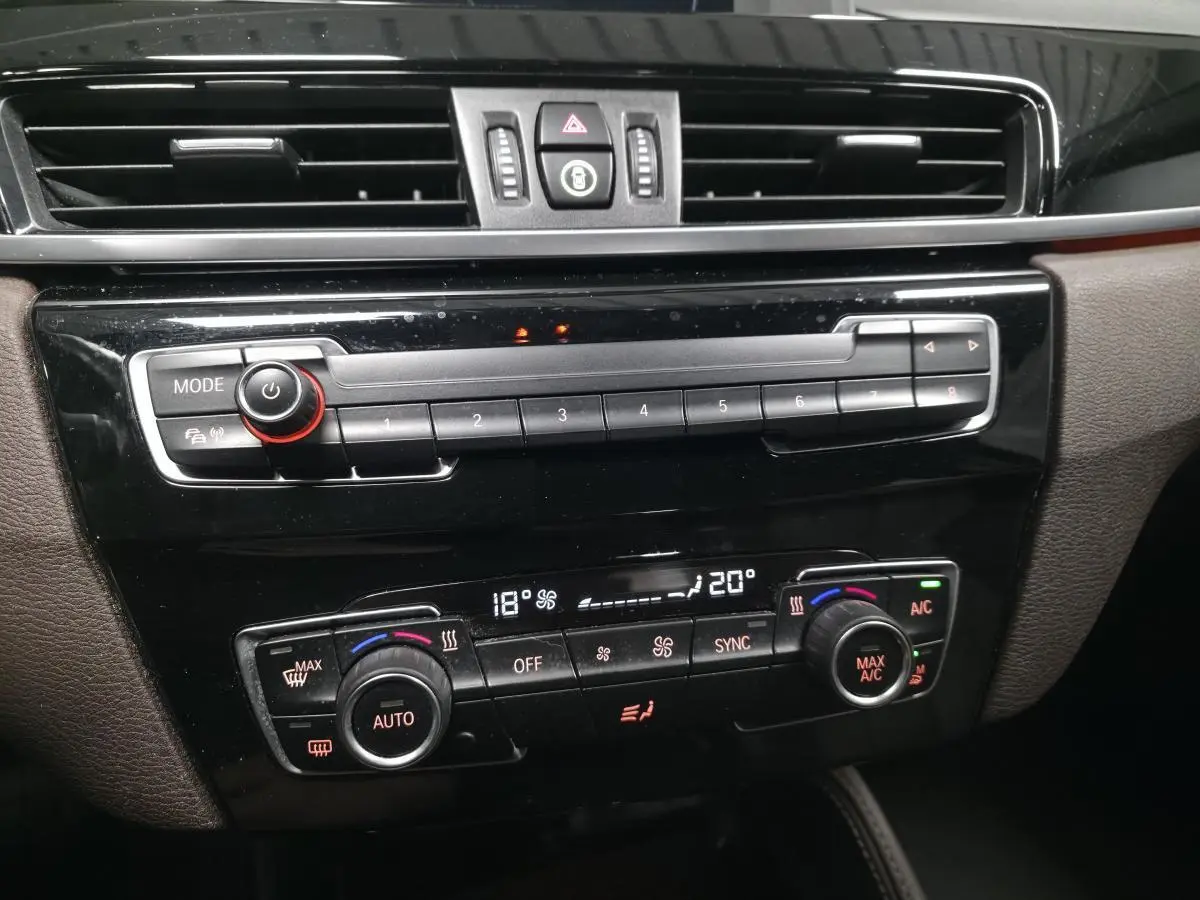 Détail de la console centrale noire brillante du BMW X1 xDrive 25d 2016 avec commandes de climatisation automatique bi-zone.