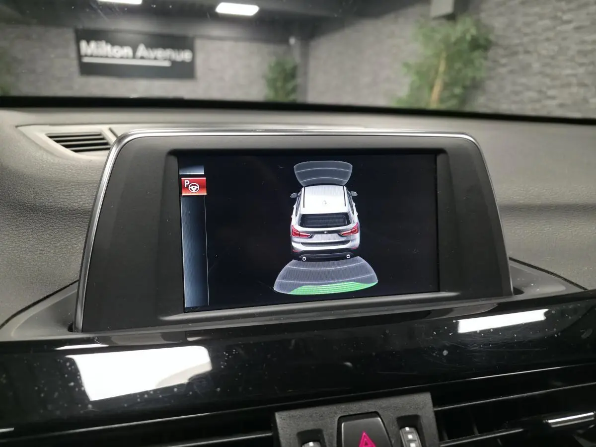 Écran central intérieur montrant l'aide au stationnement avec vue arrière virtuelle du BMW X1 xDrive 25d noir.
