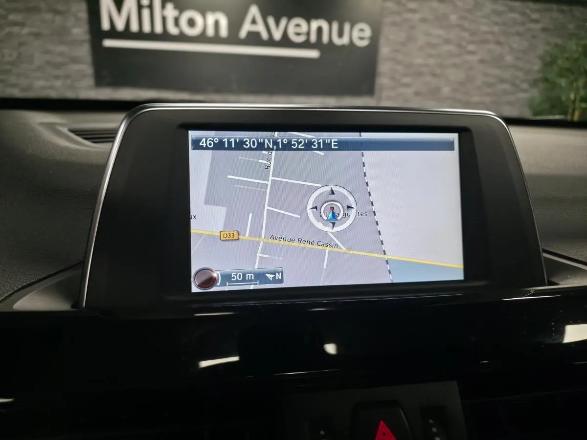 Écran central de navigation GPS dans l'habitacle d'une BMW X1 xDrive 25d noire, vue intérieure.