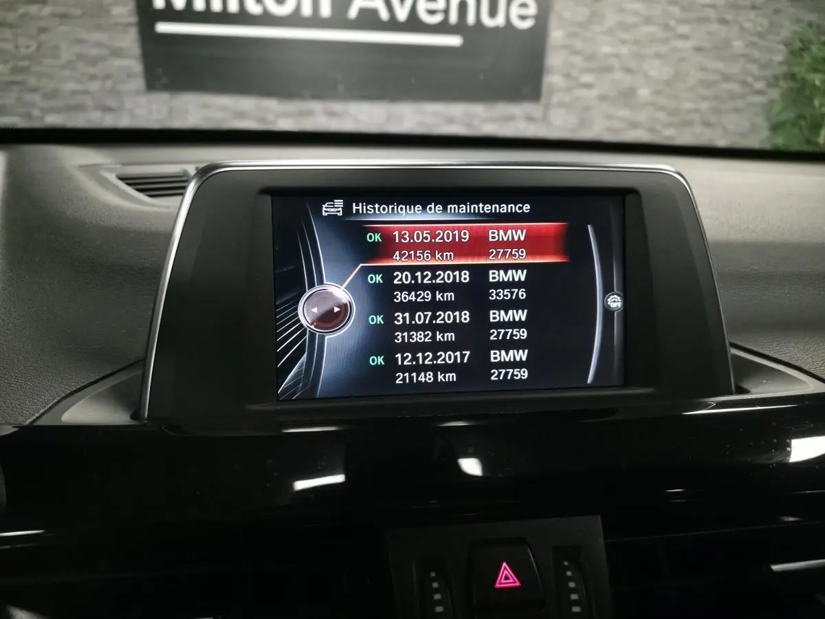 Écran central de la BMW X1 xDrive 25d 2016 affichant l'historique de maintenance dans l'habitacle noir.
