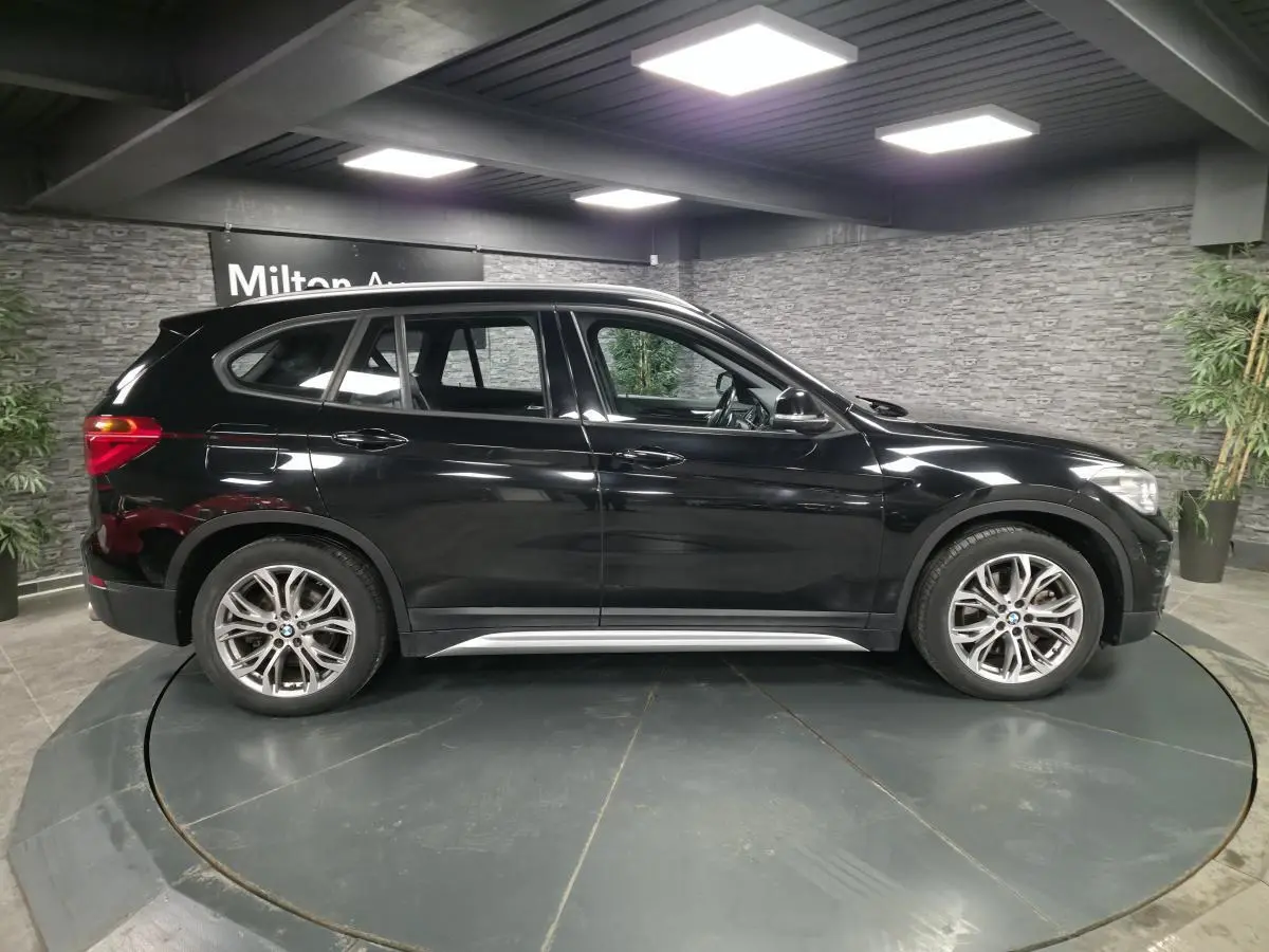 BMW X1 xDrive 25d noir vue de profil côté gauche, avec jantes alliage 18'' style 566 à rayons en Y.