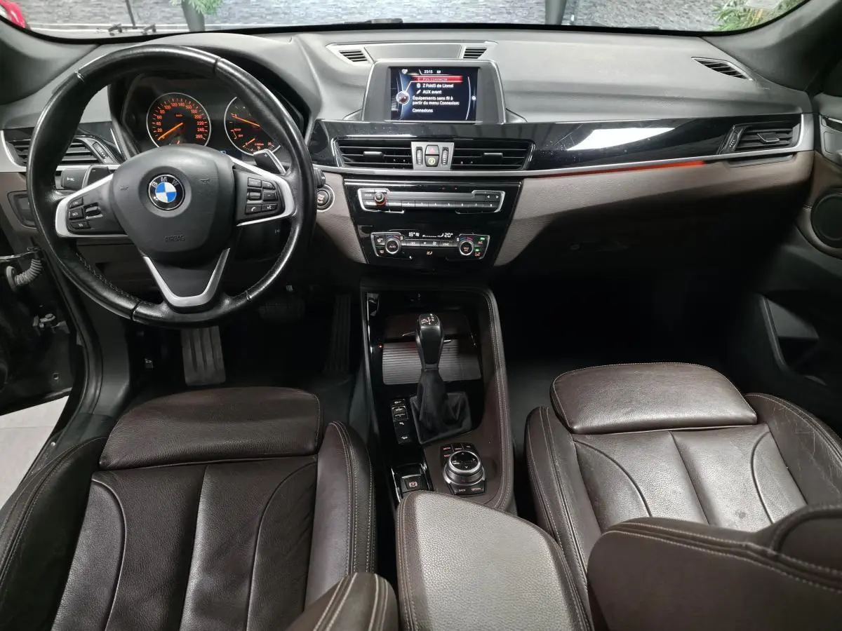 Vue intérieure avant du BMW X1 xDrive 25d 2016, sellerie cuir marron et tableau de bord avec écran central.