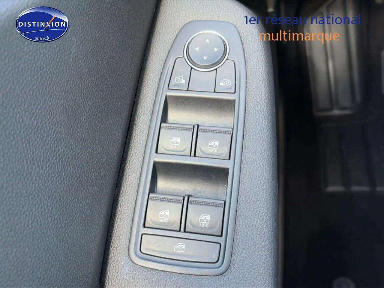 Gros plan sur les commandes de lève-vitres et rétroviseurs électriques sur la porte côté conducteur d'une Renault Clio V gris foncé.