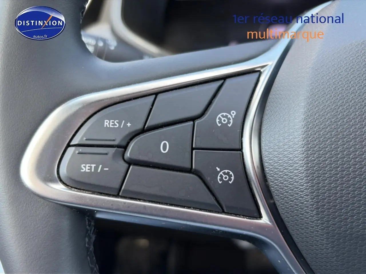 Gros plan sur les commandes de régulateur de vitesse au volant d’une Renault Clio V gris foncé.