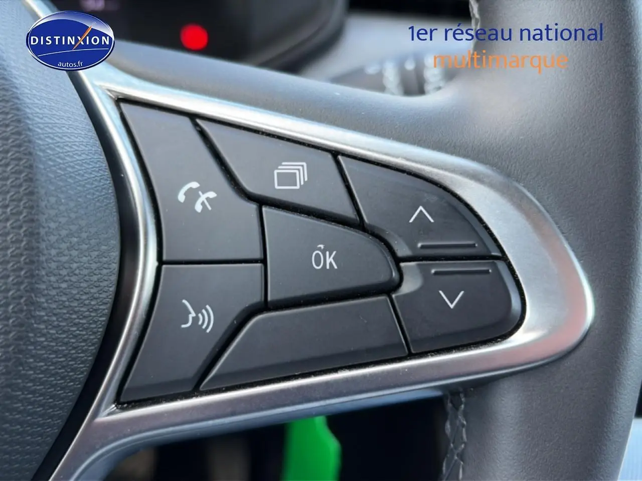 Gros plan sur les commandes multifonctions noires avec contour argenté du volant d'une Renault Clio V gris foncé.