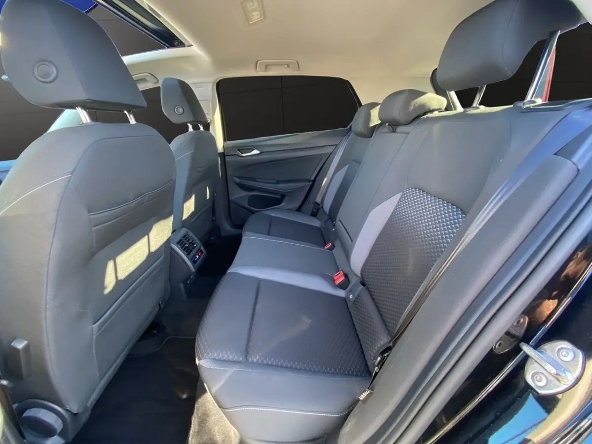 Vue latérale côté droit de l'intérieur arrière noir de la Volkswagen Golf 2.0 TDI avec toit panoramique et sièges tissu.