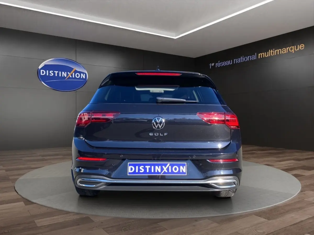 Vue arrière d'une Volkswagen Golf noire 2022 avec feux LED et logo VW bien visibles en showroom.