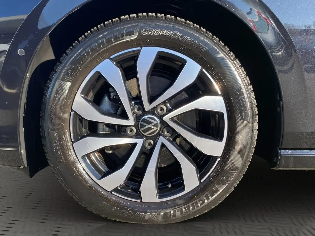 Gros plan sur la roue avant droite d’une Volkswagen Golf noire, jante alliage bicolore avec logo VW central.