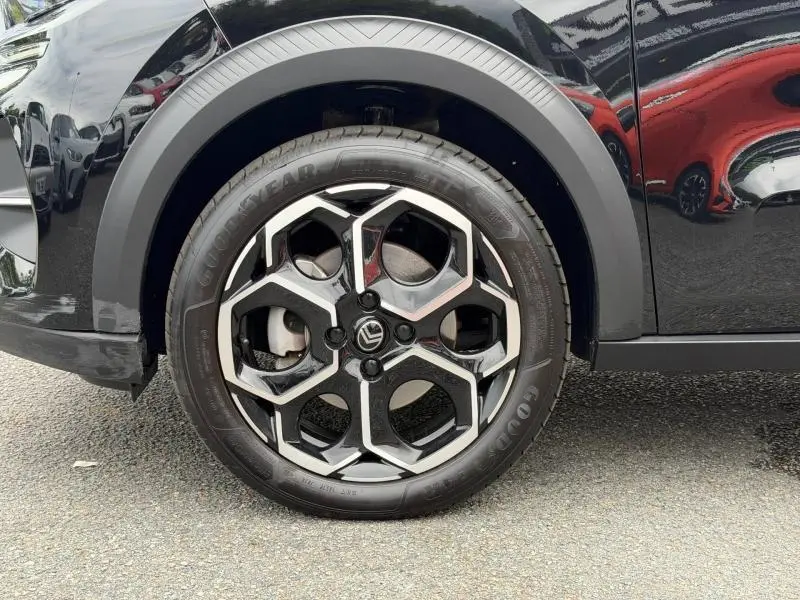 Gros plan sur la roue avant droite d'une Citroën C3 noire Perla Nera avec jante alu au design hexagonal.