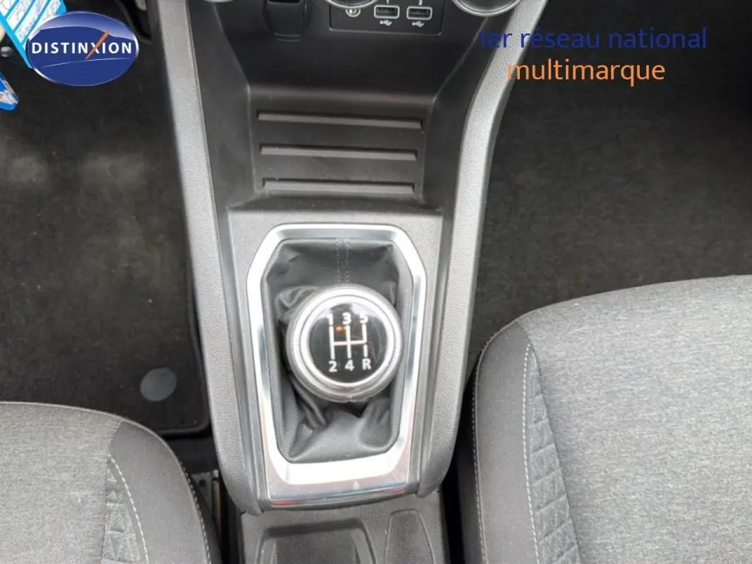 Vue rapprochée du levier de vitesses manuel de la Renault Clio blanche, avec console centrale et sièges gris.