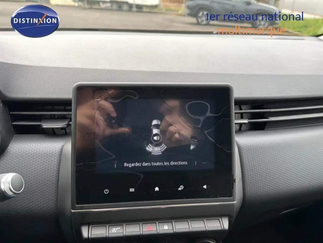 Vue rapprochée de l’écran central tactile du tableau de bord d’une Renault Clio blanche, affichant l’aide au stationnement.