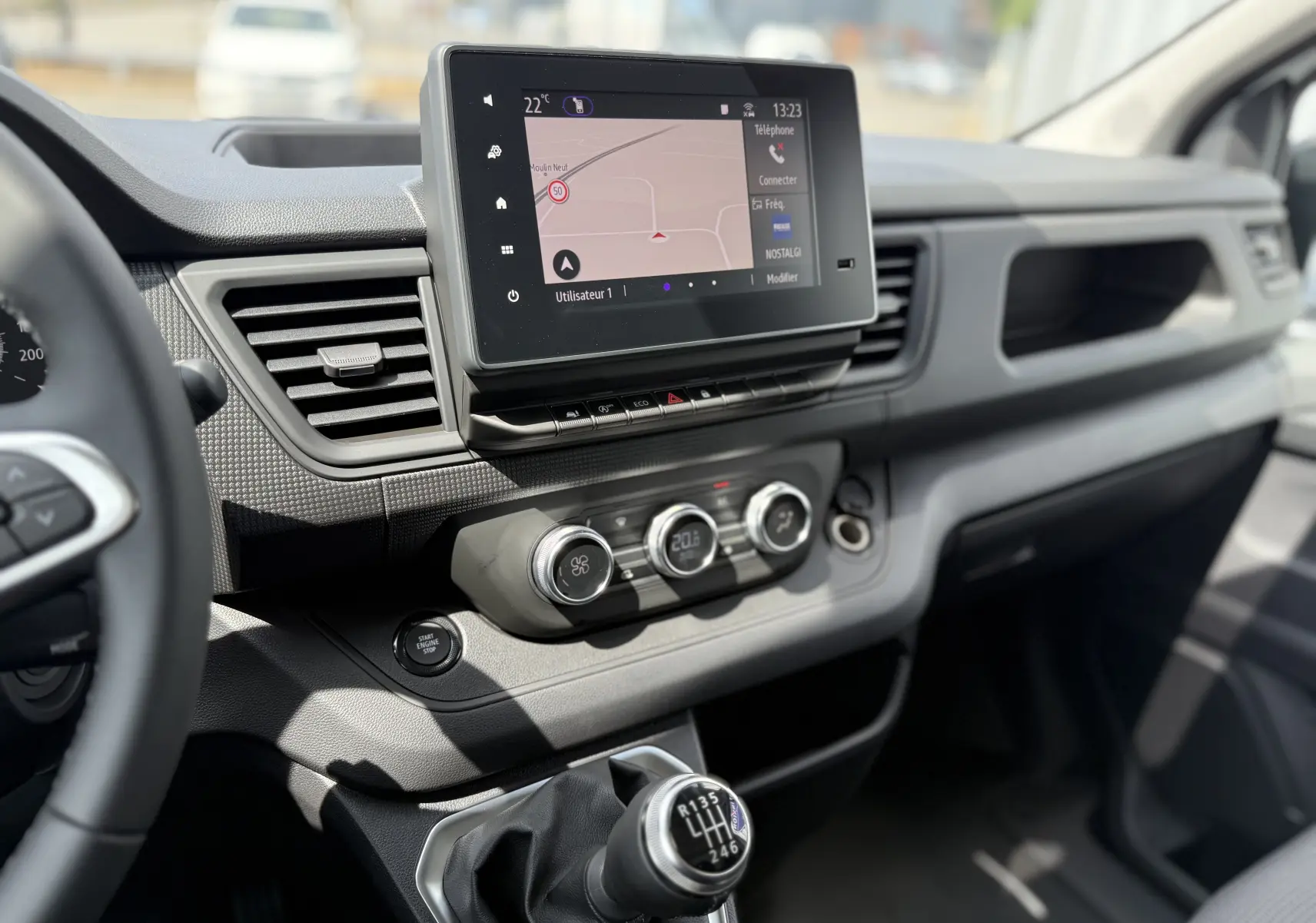 Vue intérieure du tableau de bord du Renault Trafic Fourgon blanc 2025, avec écran tactile et levier de vitesses manuel.