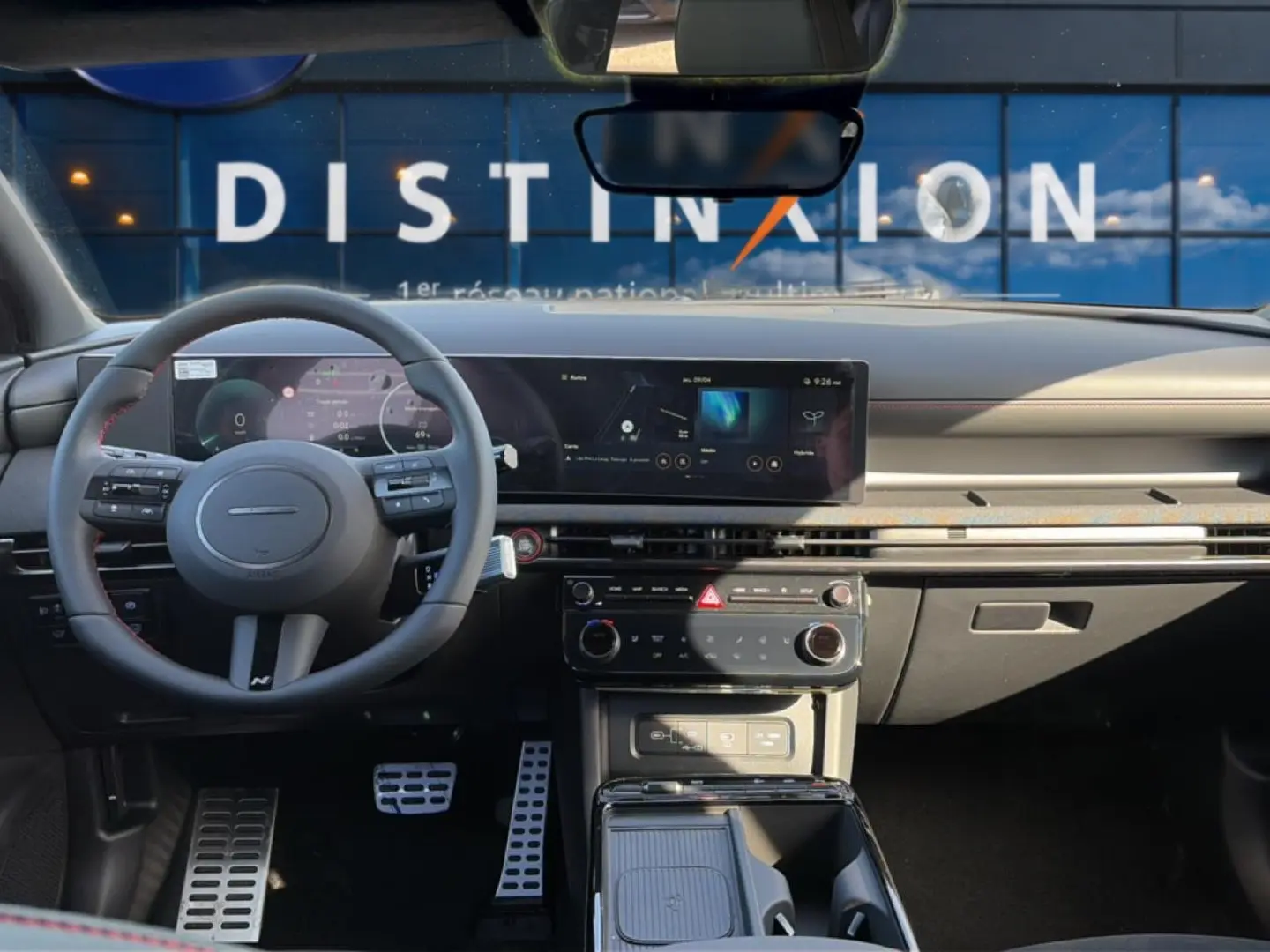 Vue intérieure du tableau de bord et volant cuir gris du Hyundai Tucson 2026 avec écran tactile panoramique et pédalier sport.