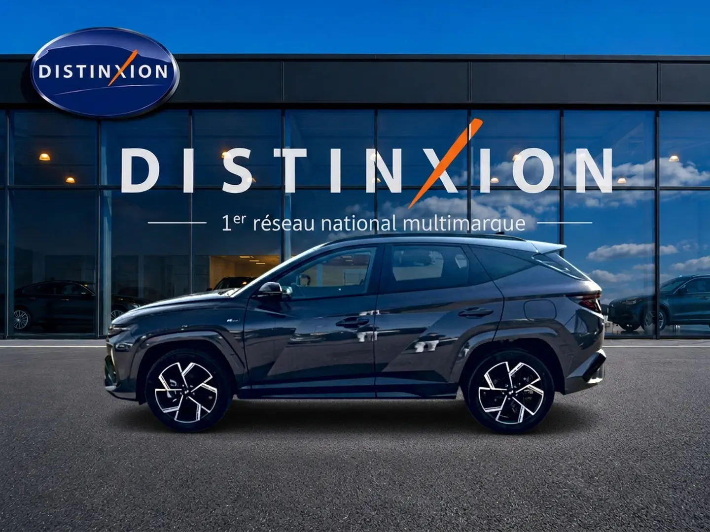 Vue latérale droite du Hyundai Tucson 2026 gris ecotronique avec jantes alliage et détails N Line devant vitrine Distinxion.
