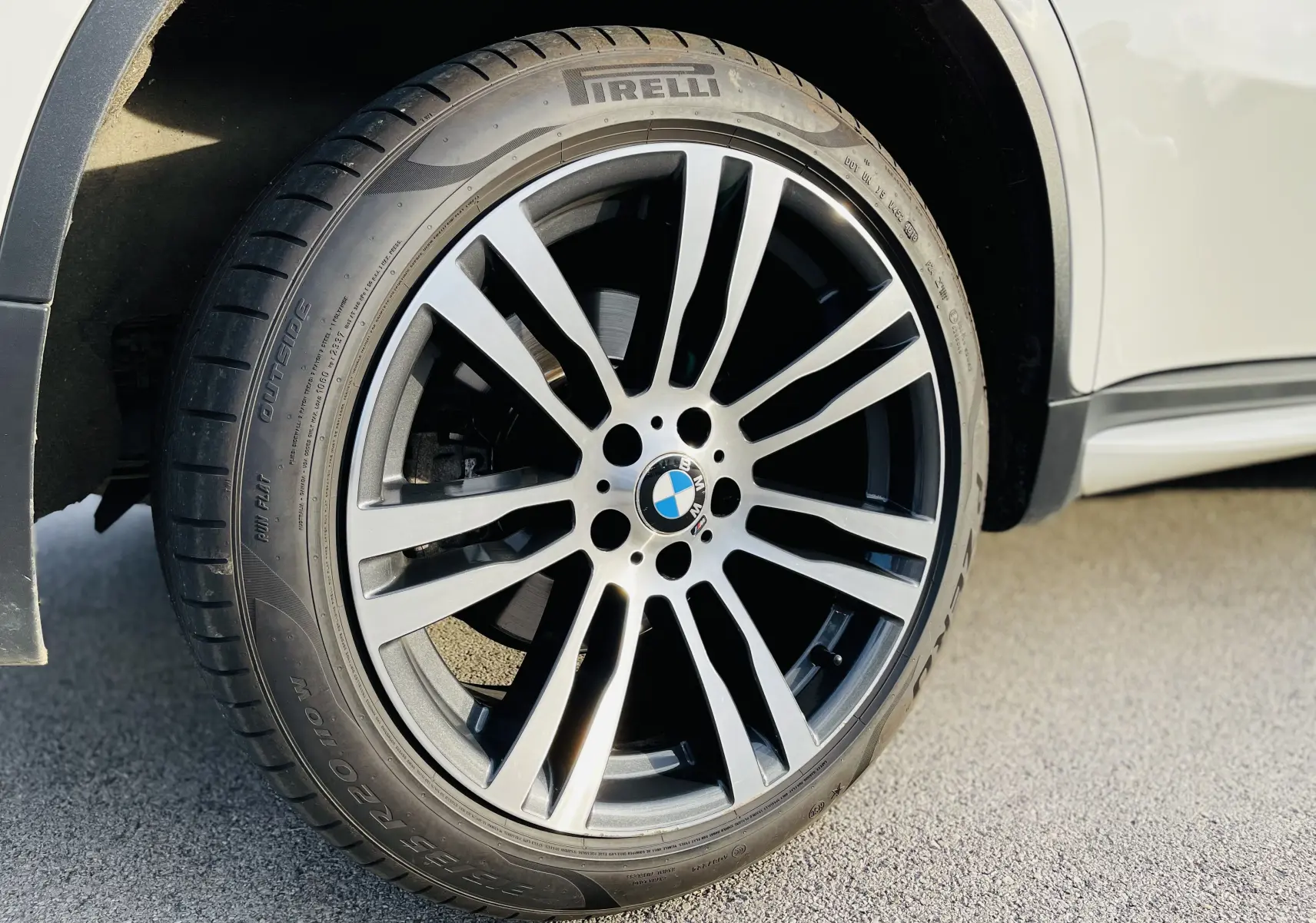 Gros plan sur la roue avant gauche du BMW X6 blanc, mettant en valeur la jante M sport et le pneu Pirelli.