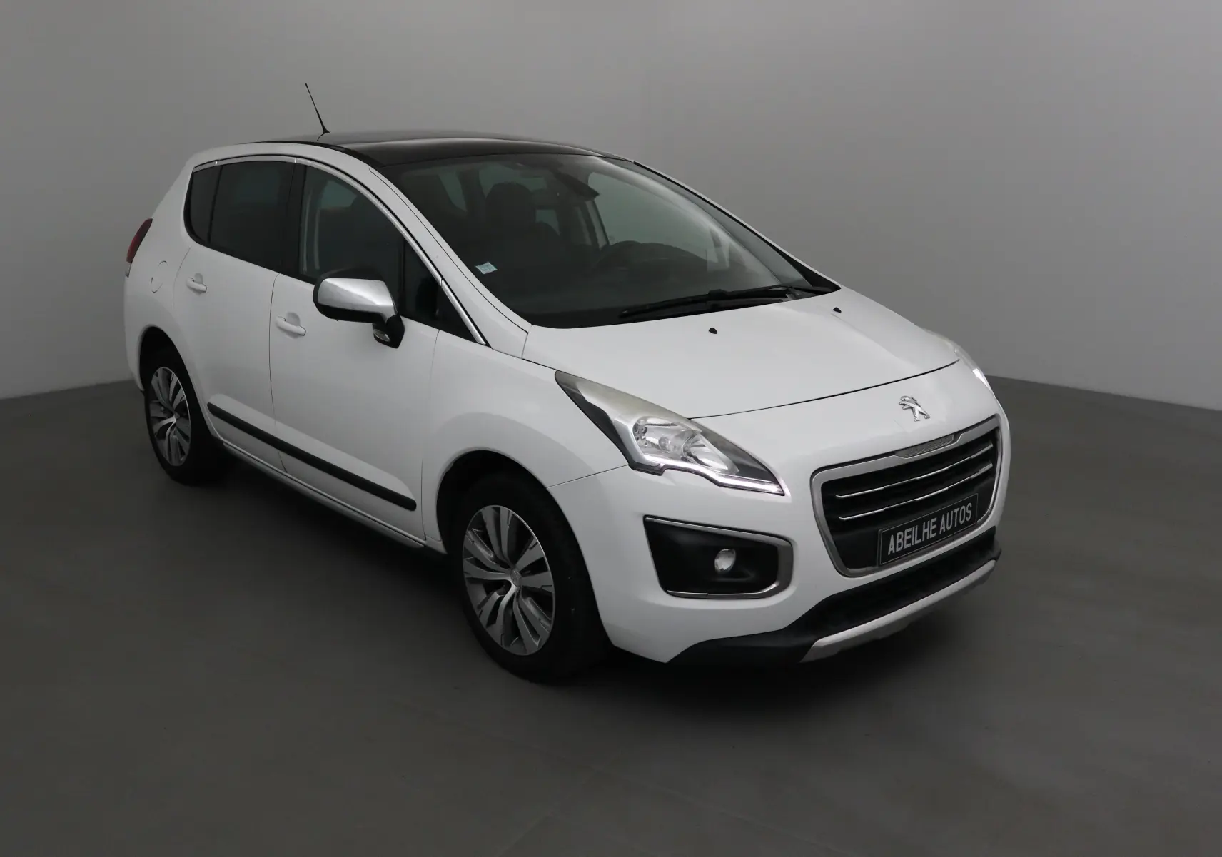 Peugeot 3008 blanc vue 3/4 avant droit avec toit noir et jantes alliage dans un studio gris.