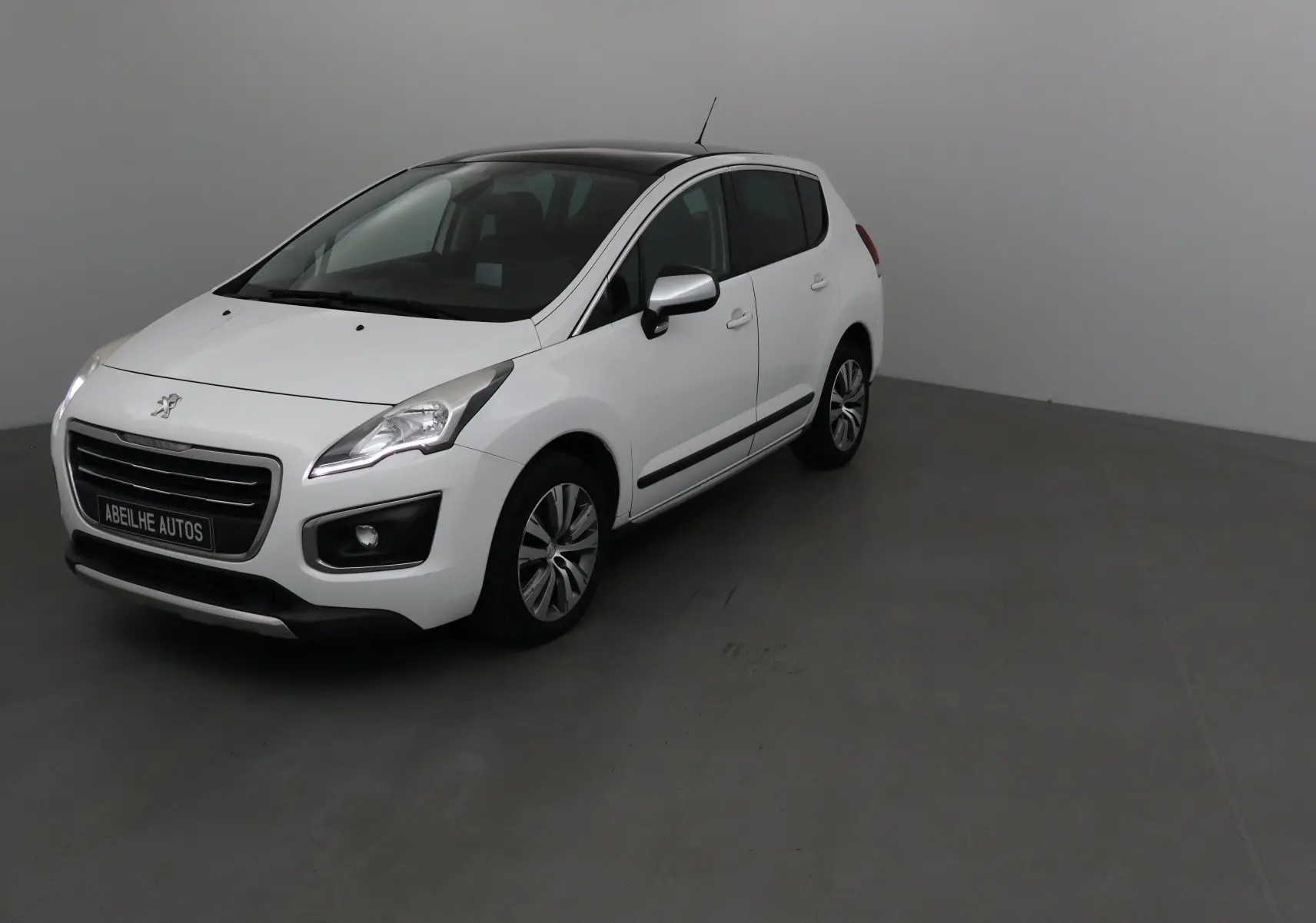 Peugeot 3008 blanc vue 3/4 avant droit avec toit noir et jantes alliage dans un studio gris.