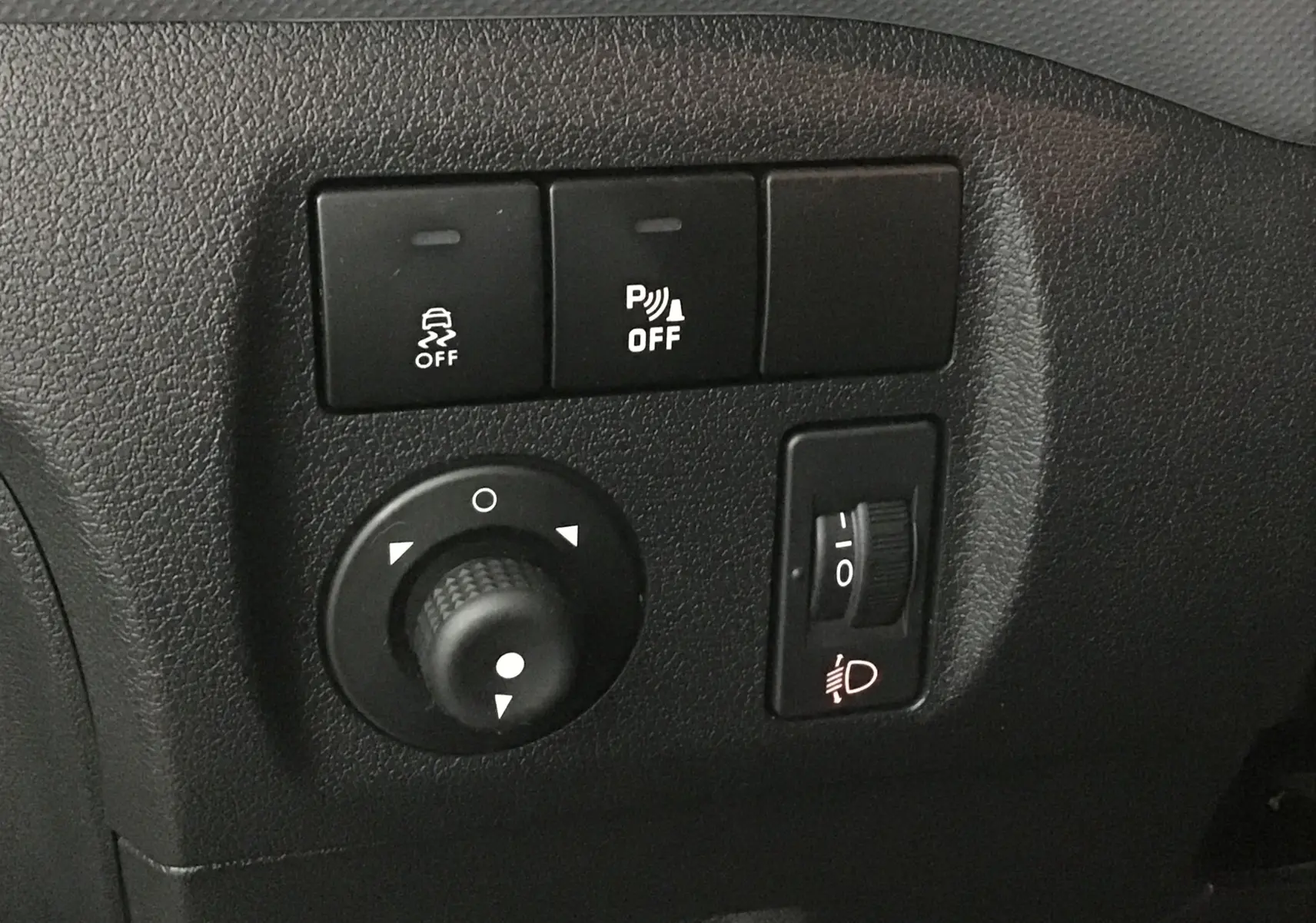 Gros plan sur les commandes de réglage des phares et de l'ESP dans l'habitacle d'un Citroën Berlingo blanc de 2018.