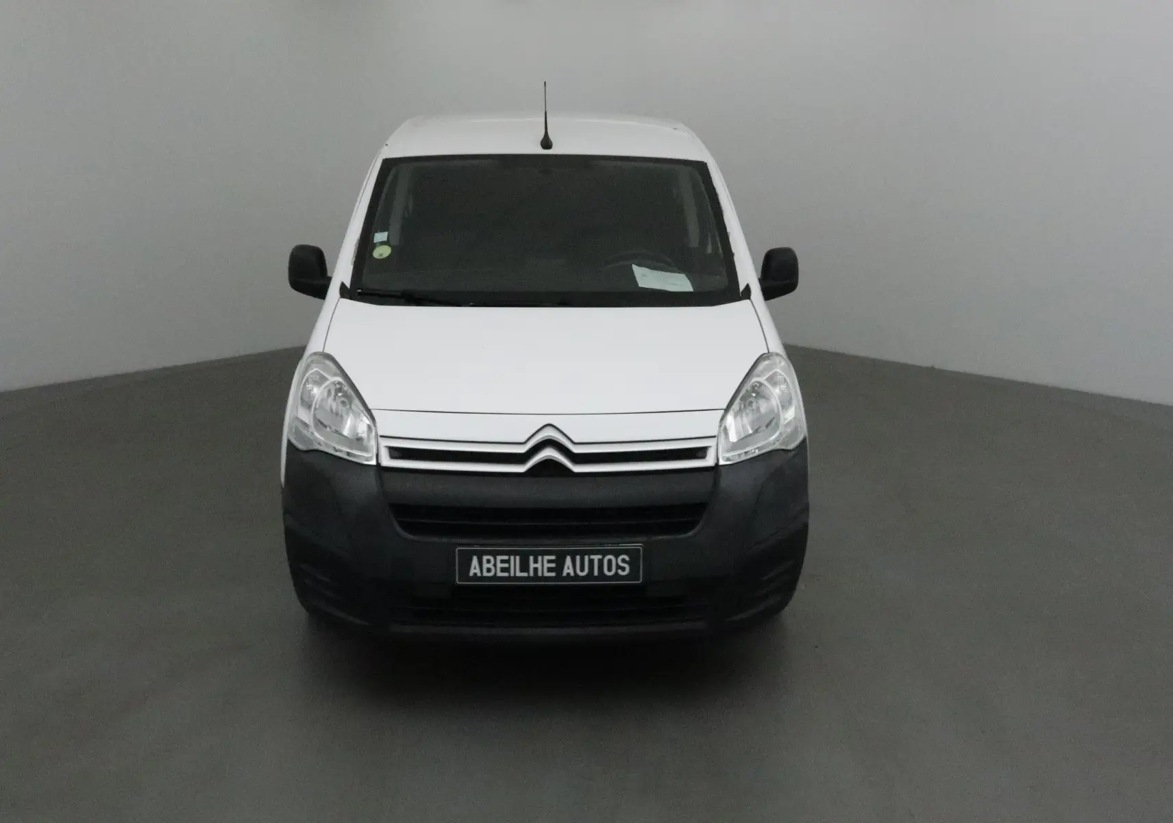 Vue frontale d'un Citroën Berlingo blanc avec pare-chocs noir et plaque Abeilhe Autos visible.