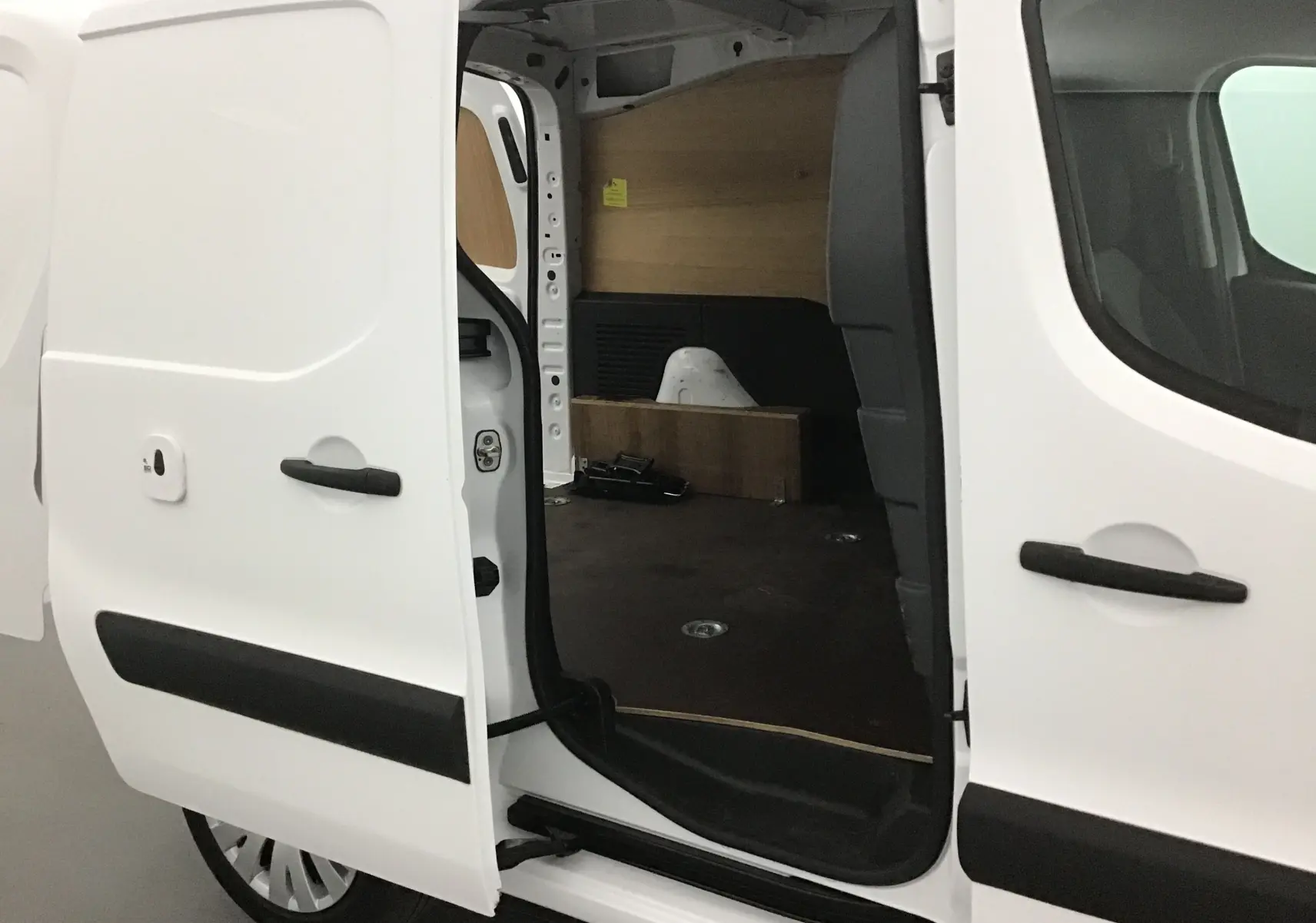 Vue latérale gauche du Citroën Berlingo blanc 2018 avec porte coulissante ouverte montrant l'intérieur utilitaire avec habillage bois.