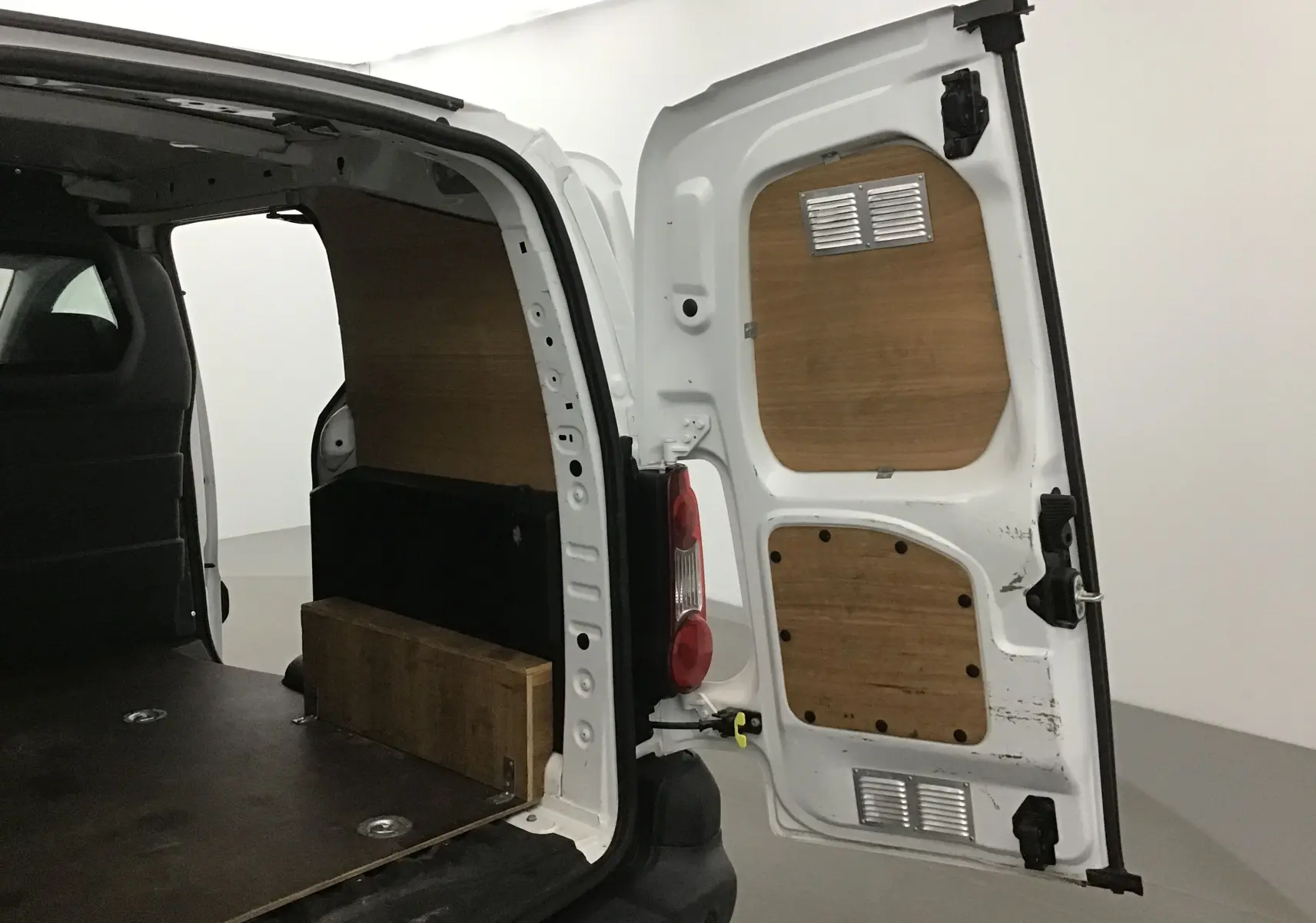 Vue arrière droite ouverte d'un Citroën Berlingo blanc 2018 avec aménagement bois intérieur visible dans l'espace de chargement.