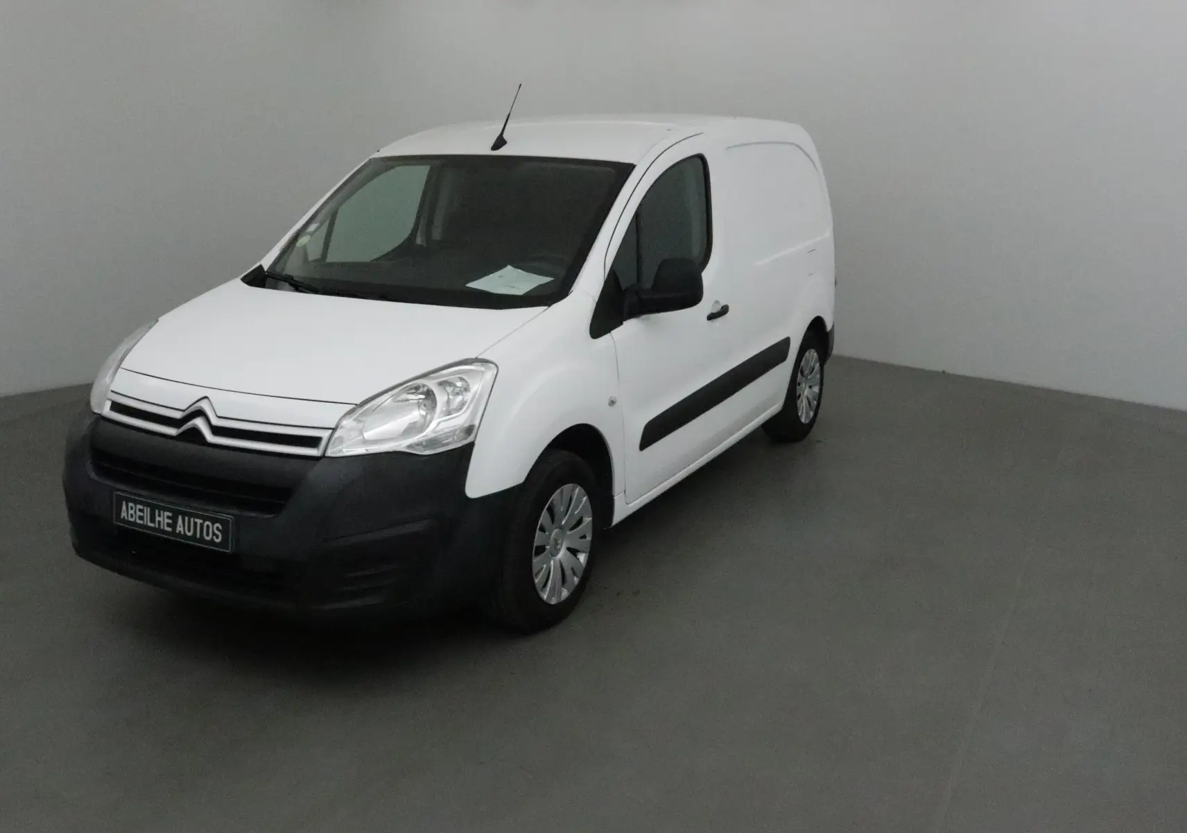 Citroën Berlingo blanc vu en 3/4 avant droit avec pare-chocs noirs et jantes acier en intérieur neutre.