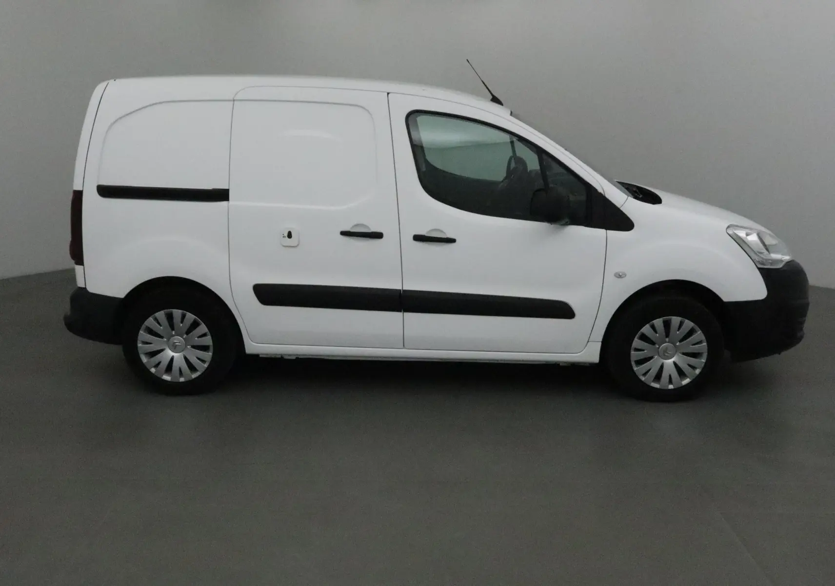 Profil côté gauche d'un utilitaire blanc Citroën Berlingo 2018 avec portes latérales coulissantes et protections noires.