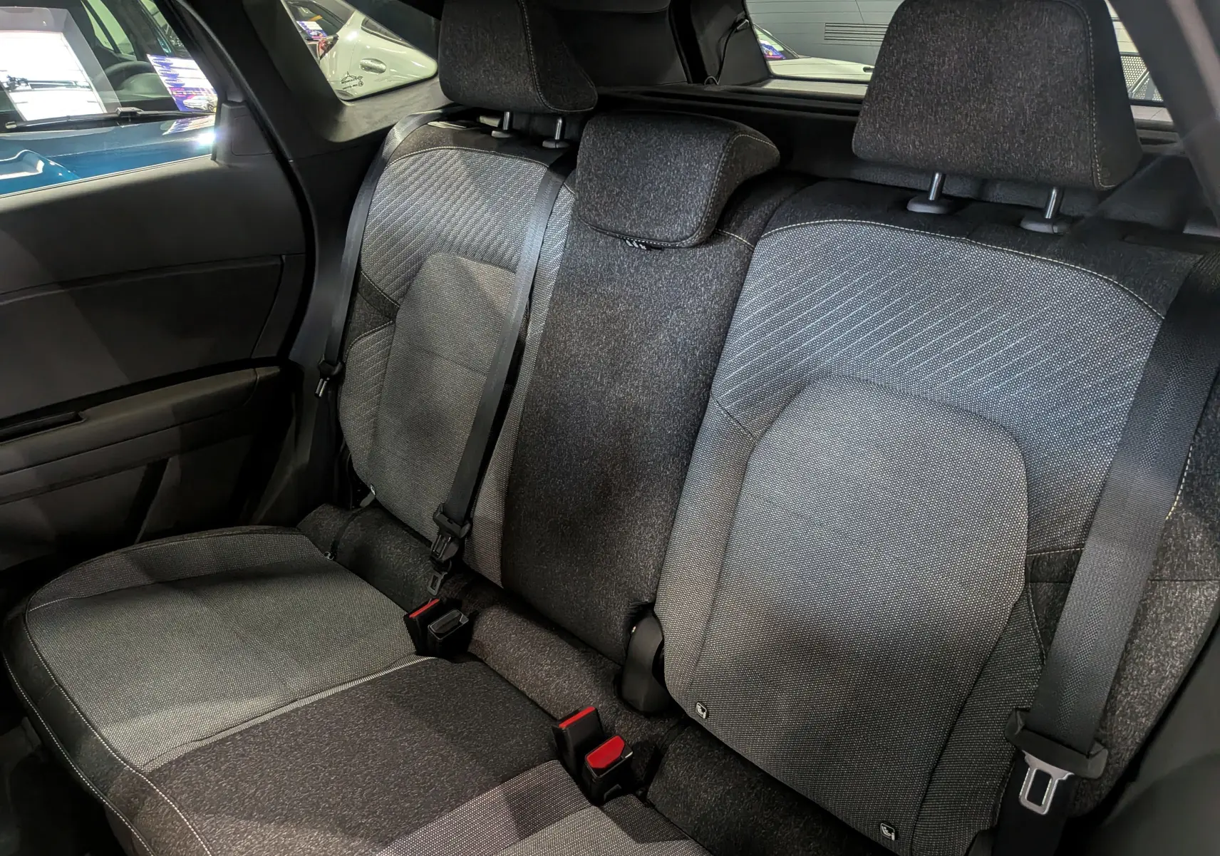 Vue intérieure arrière montrant les sièges arrière en tissu gris du Renault Symbioz E-Tech full hybrid 2025.