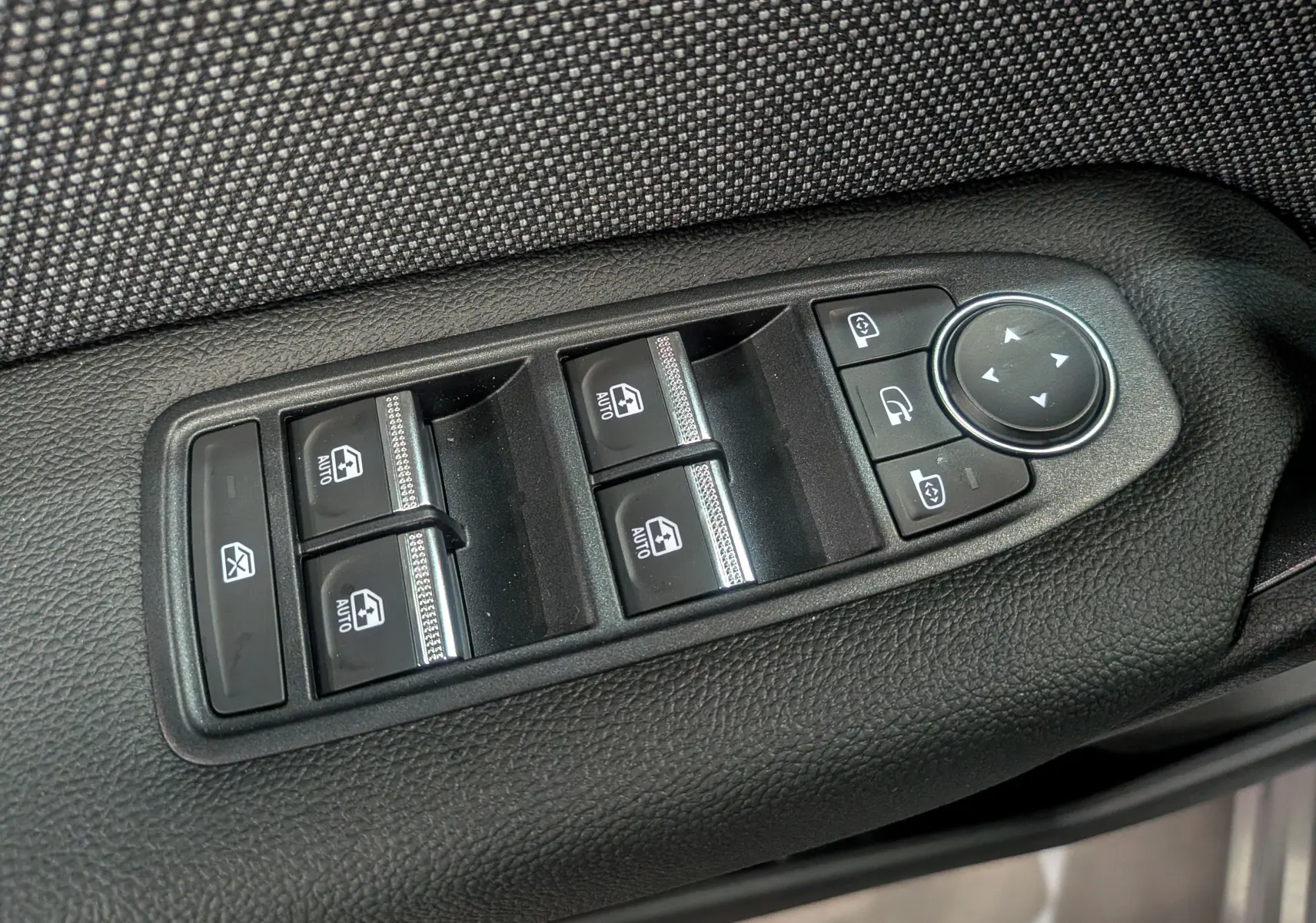 Panneau de commandes des vitres et rétroviseurs sur la porte côté gauche d’une Renault Symbioz gris Cassiopé.