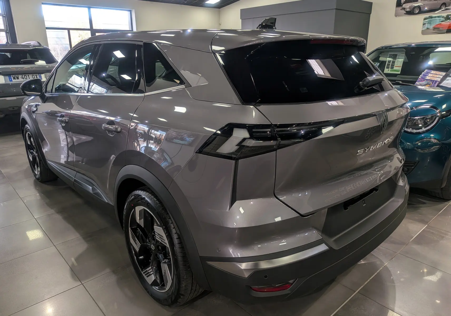 Vue 3/4 arrière droite du Renault SYMBIOZ gris Cassiopé avec feux arrière noirs et jantes bicolores en showroom.