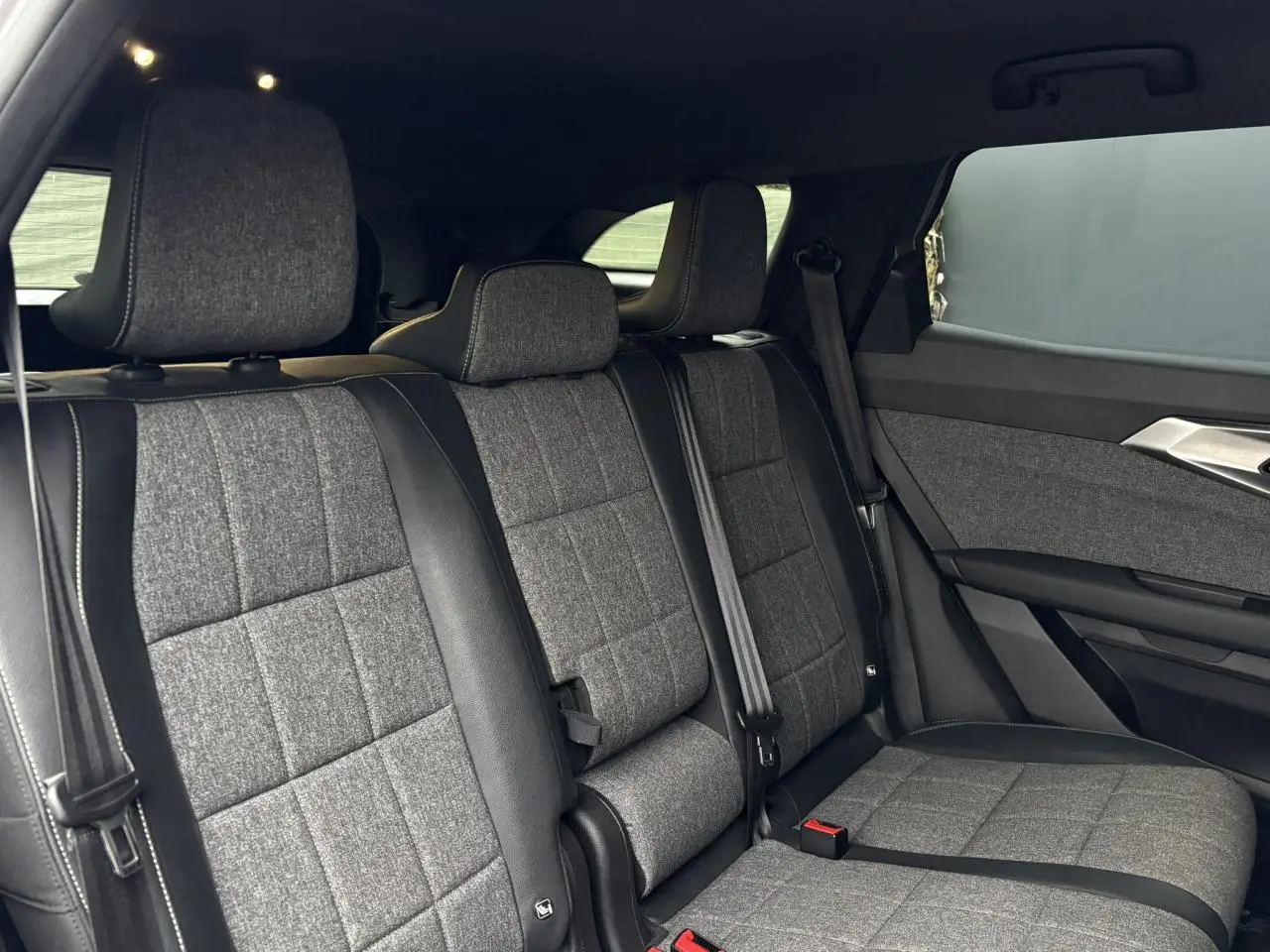 Vue latérale intérieure des sièges arrière en tissu gris et cuir noir du Renault Espace 2024 E-Tech Full Hybrid.