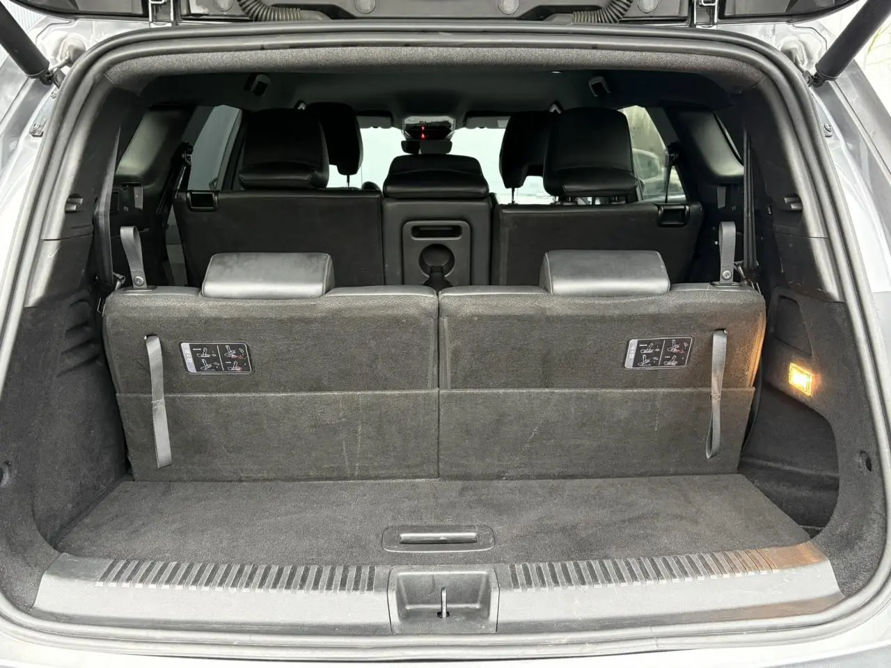 Vue arrière ouverte du coffre du Renault Espace gris, montrant la troisième rangée de sièges relevée en tissu noir.