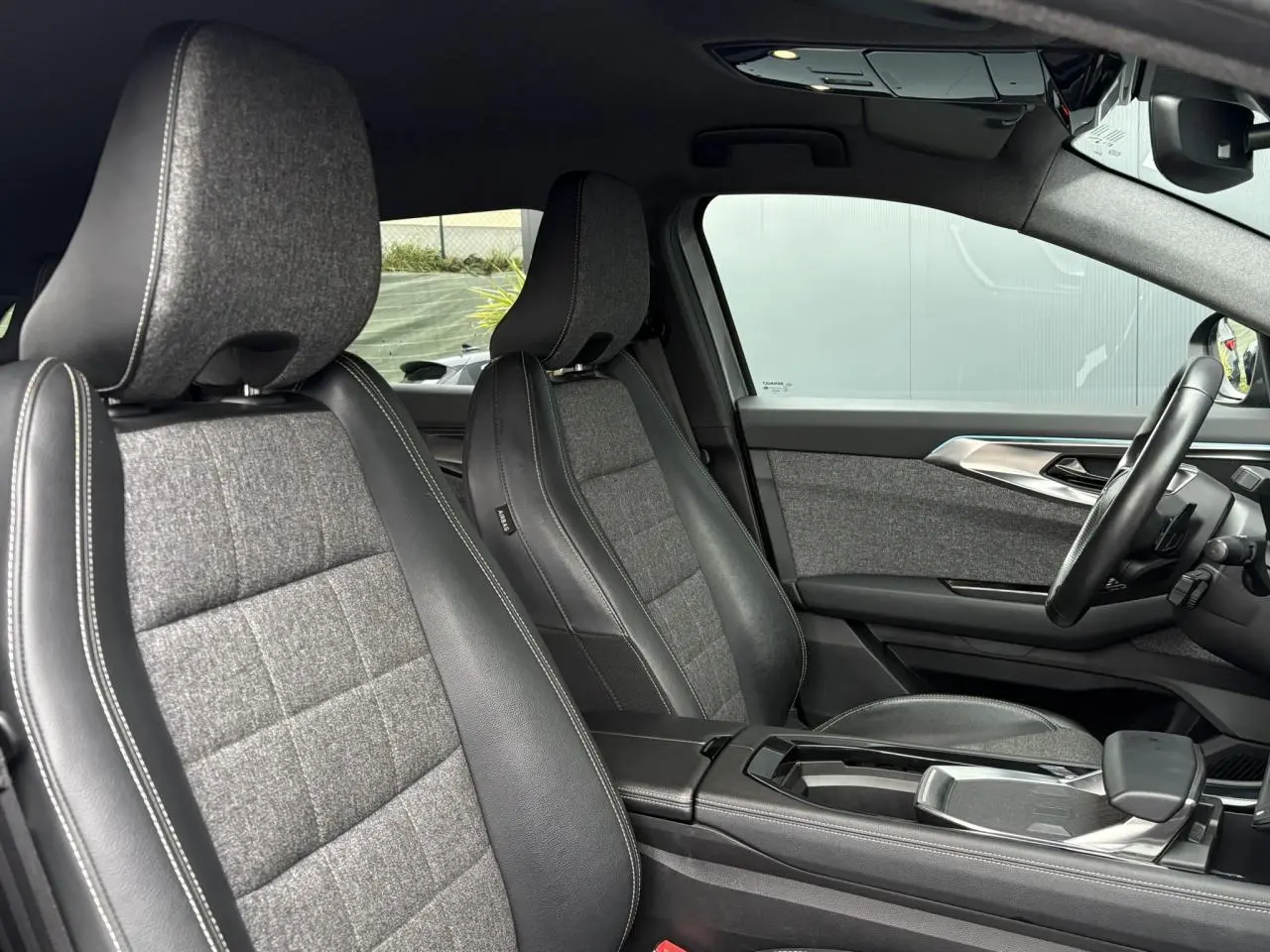 Vue intérieure côté droit du Renault Espace 2024, sièges tissu et cuir gris avec surpiqûres blanches et tableau de bord moderne.