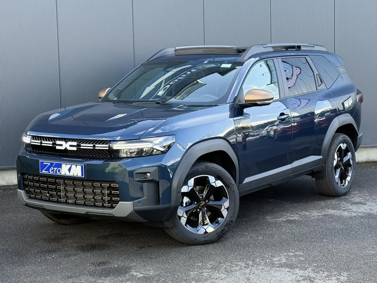 Vue 3/4 avant du Dacia Bigster 2026 bleu indigo avec jantes alliage noires et rétroviseurs bronze.