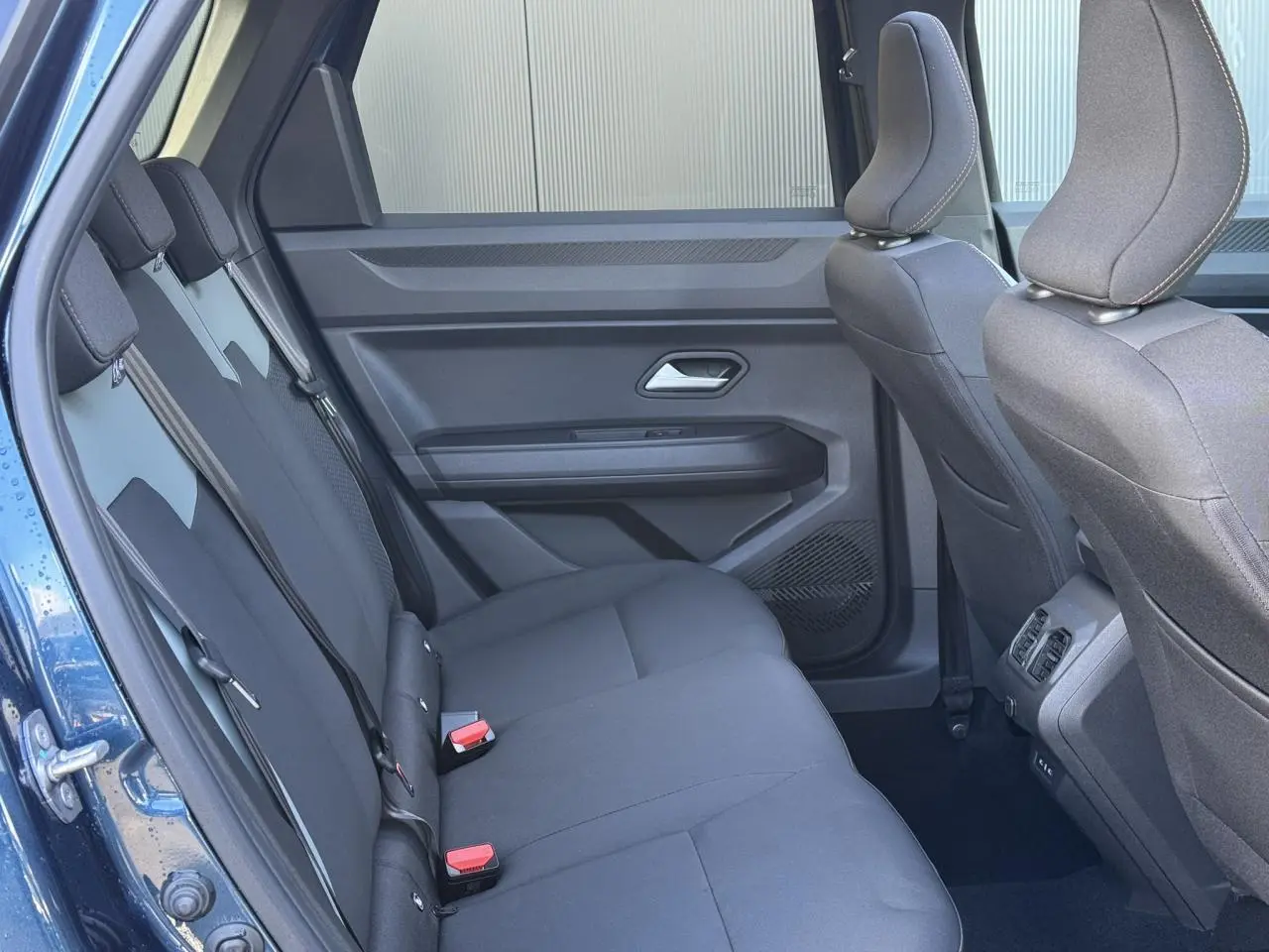 Vue intérieure côté gauche montrant la banquette arrière noire du Dacia Bigster Bleu Indigo avec portes ouvertes.