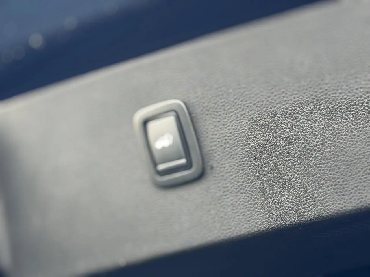 Bouton hayon électrique en gros plan sur la garniture intérieure bleu indigo du Dacia Bigster 2026.