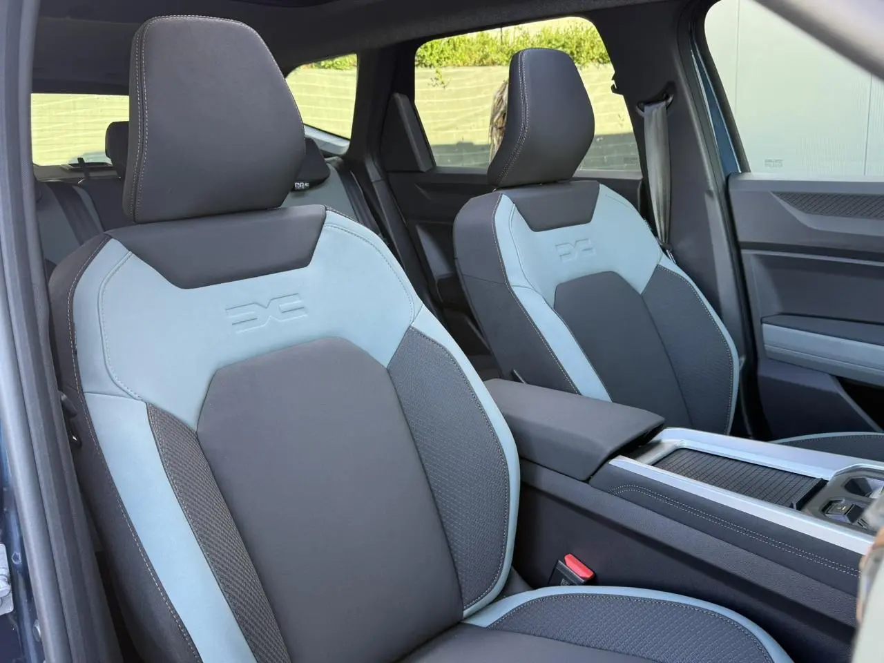 Vue intérieure sur les sièges avant gris clair et foncé du Dacia Bigster 2026 avec accoudoir central et porte-gobelets.