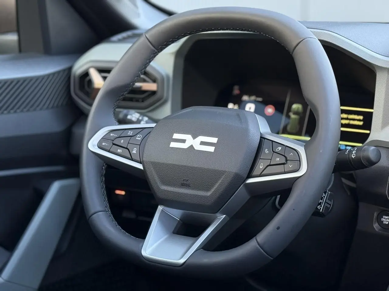 Gros plan sur le volant noir du Dacia Bigster 2026 avec commandes intégrées et tableau de bord numérique en arrière-plan.